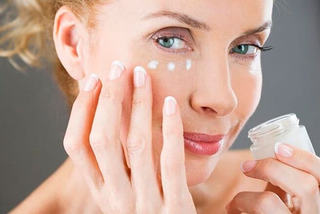 Woman applying face cream with anti-aging effect