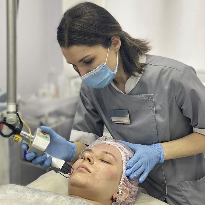 A cosmetologist performs a laser fractional facial skin rejuvenation procedure